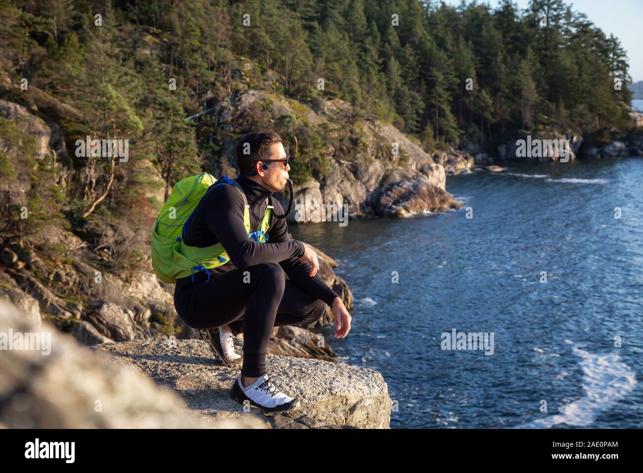 Ritratto di un avventuroso uomo latino acqua potabile al di fuori in natura durante un nuvoloso e soleggiato al tramonto. Presa faro nel parco, baia a ferro di cavallo, West Foto Stock