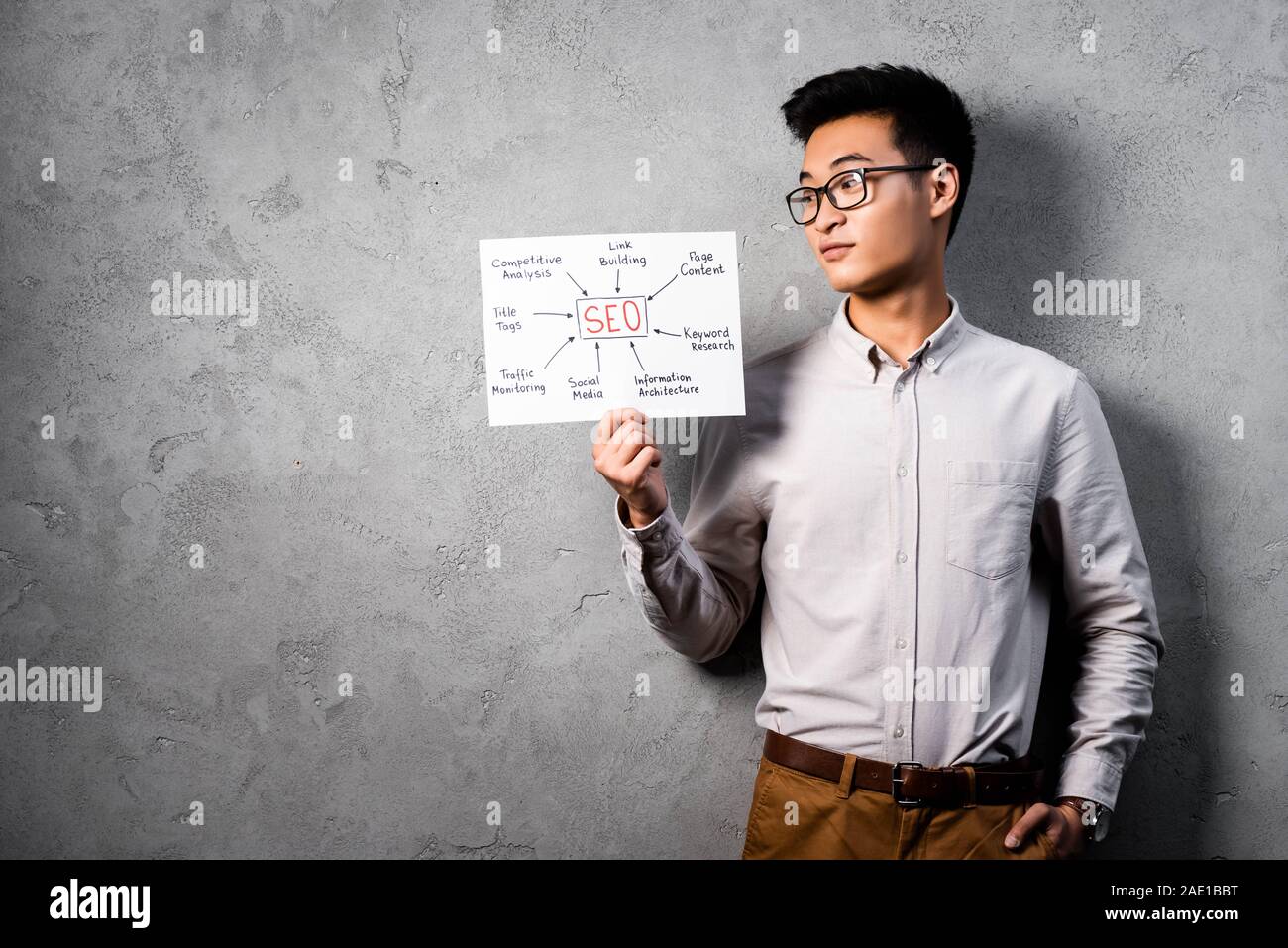 Asian seo manager di detenzione e guardando la carta con le parole il concetto di seo Foto Stock