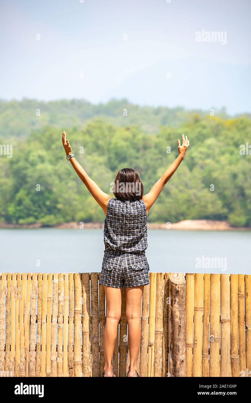 Donne alzando le braccia e sullo sfondo le montagne e acqua al serbatoio Chakrabongse , Prachinburi in Thailandia. Foto Stock