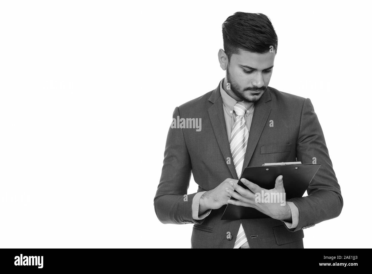 Bel giovane imprenditore indiano lettura sulla clipboard Foto Stock