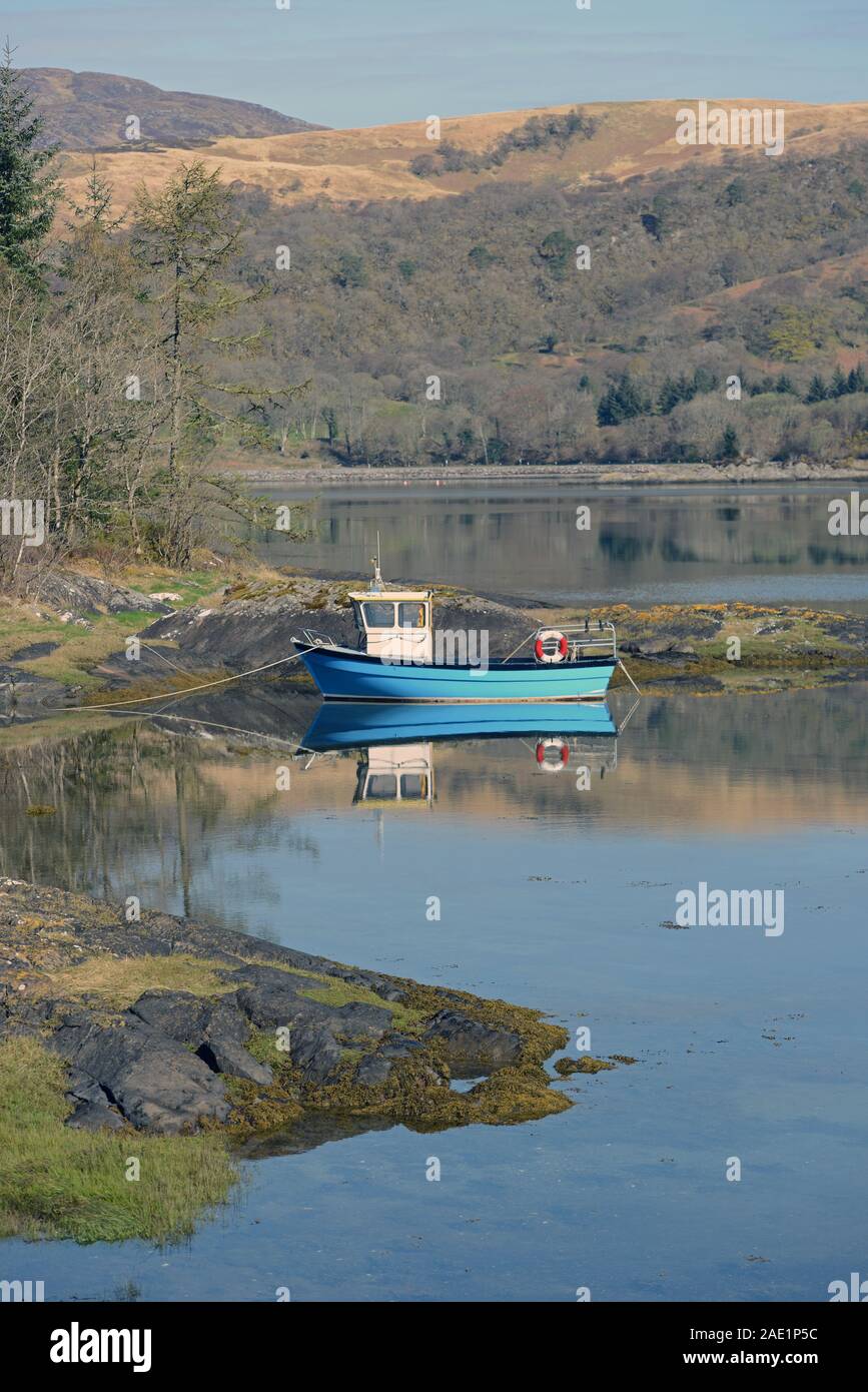 Una piccola barca da pesca riflette pacificamente nelle calme acque del Loch CRERAN, SCOZIA Foto Stock