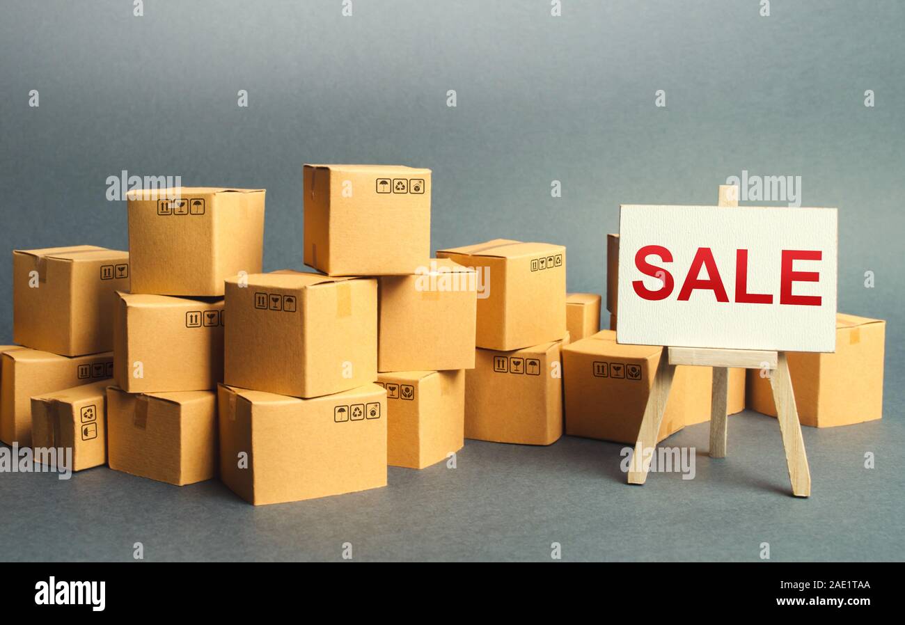 Molte scatole di cartone e un segno di stand con la parola vendita. Vendita di beni e prodotti a prezzi competitivi e promozioni. grossi sconti sui beni di th Foto Stock