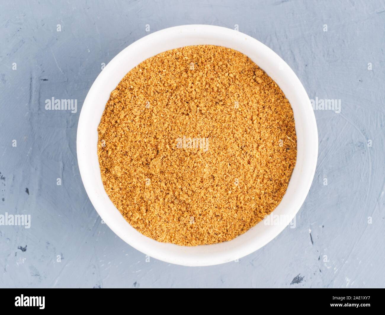 Spice masala in una ciotola bianco su un cemento grigio Sfondo. Mangiare sano concetto Foto Stock