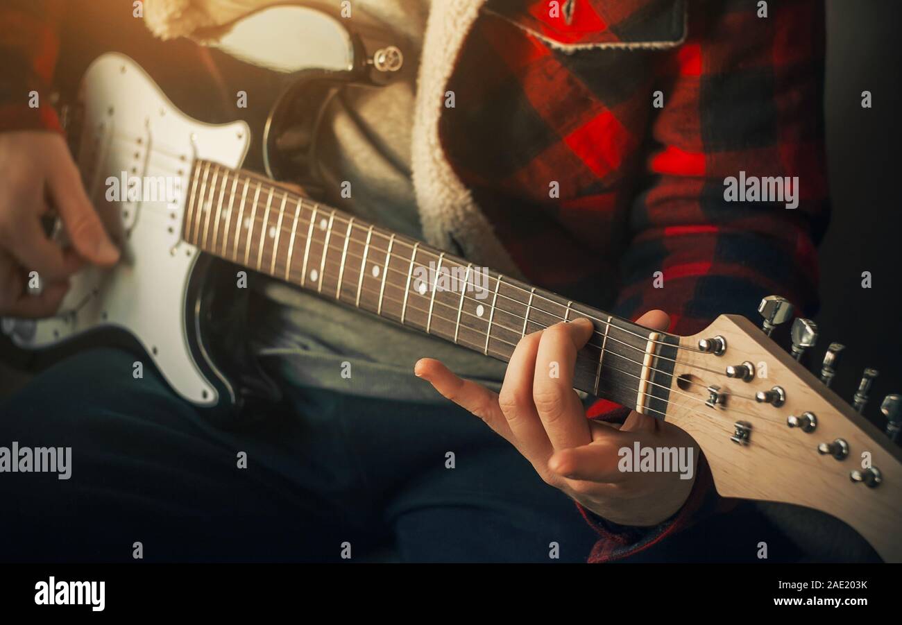Un chitarrista in una controllata di rosso e giacca nera riproduce una improvvisata rock sintonizzarsi su un bianco e nero con la chitarra elettrica, illuminato dalla luce del sole. Foto Stock