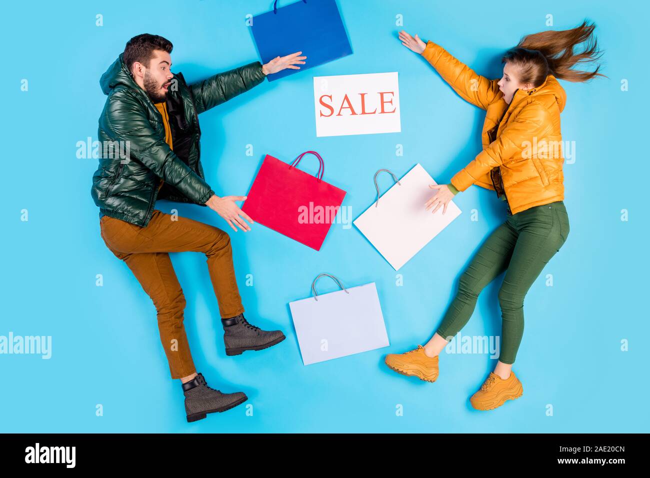 Parte superiore al di sopra ad alto angolo di visione per tutta la lunghezza del corpo lato di dimensione della foto del profilo di Crazy giovane che giace tra i pacchetti e tablet in vendita in pantaloni Marrone Verde isolato Foto Stock