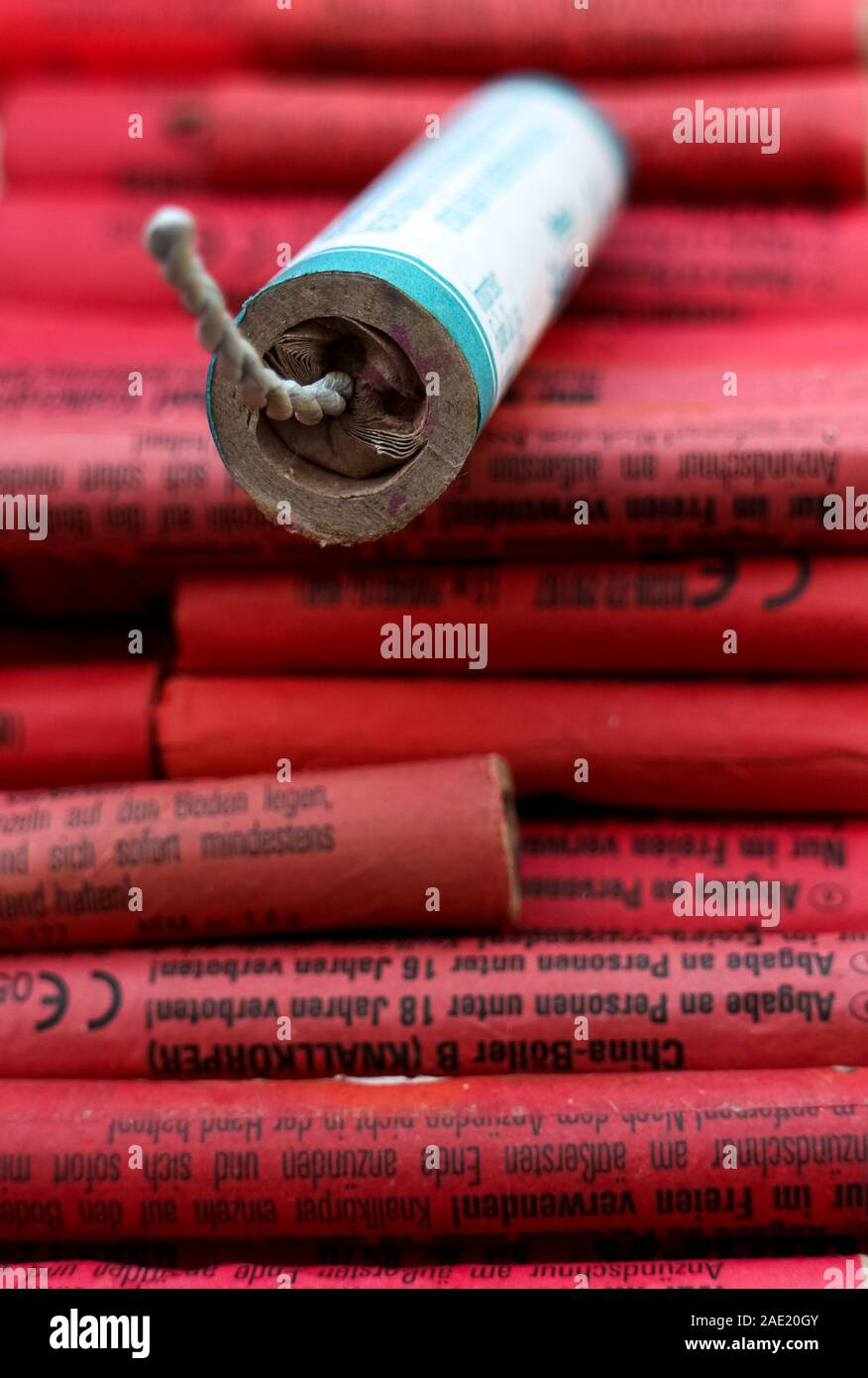Berlino, Germania - 5 Dicembre 2019: Giornale di tenuta un petardo cinese su una pila di rosso petardi ("Boller") dal mercato tedesco. Foto Stock