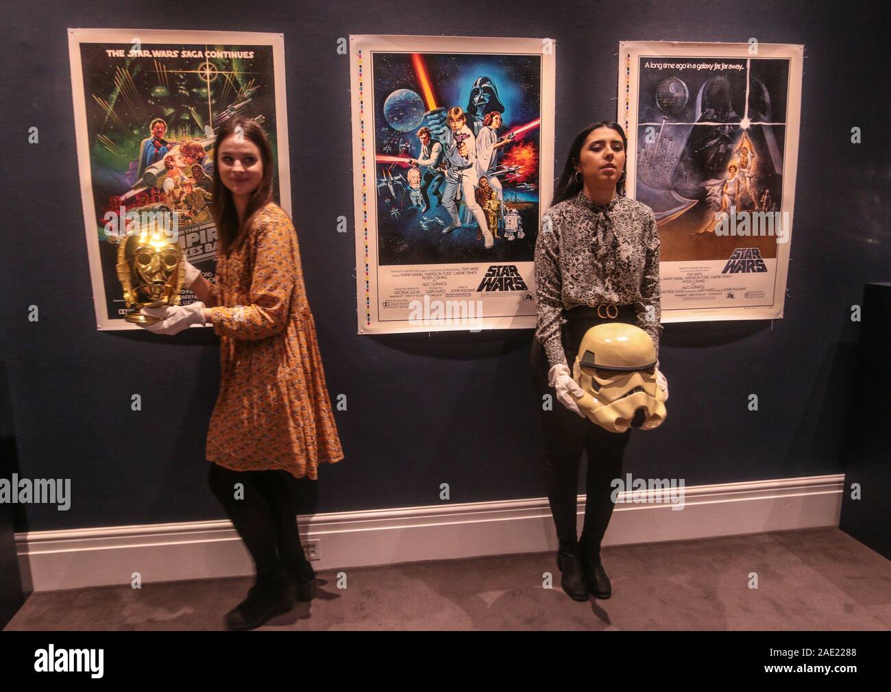 Londra UK venerdì 06 dicembre 2019 due assistenti galleria tenendo premuto il ritorno dello Jedi promozionali C-3PO casco (est. £15,000 - 25,000). Anche sulla fascia alta è un lucido promozionali oro C-3PO testa dal ritorno dello Jedi (1983) pari a £ 15.000 - 25.000 ($19.400-32,300) e il prototipo di un Imperiale Stormtrooper casco (1976) da Star Wars: Episodio IV - Una nuova speranza (est. £30.000 - 60.000).La più notevole voce tra i 100 lotti è un prototipo dell'iconico Imperial Stormtrooper casco da Star Wars: Episodio IV - Una nuova speranza (1977), stimato per andare tra £30.000 - 60.000 ($38,800-77,60 Foto Stock