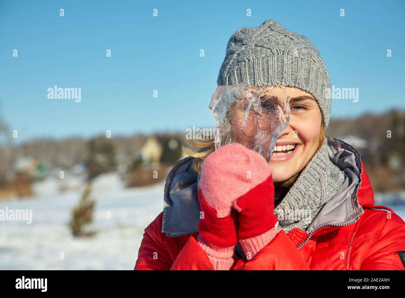 donna allegra con un pezzo di ghiaccio in mano in inverno. Foto Stock