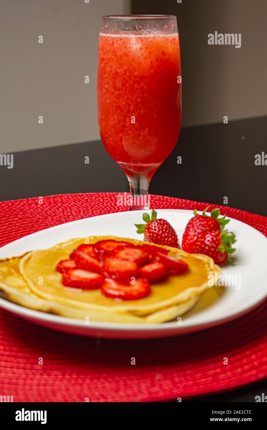 Pancake fatti in casa con fragole e sciroppo nel piatto bianco. Foto Stock