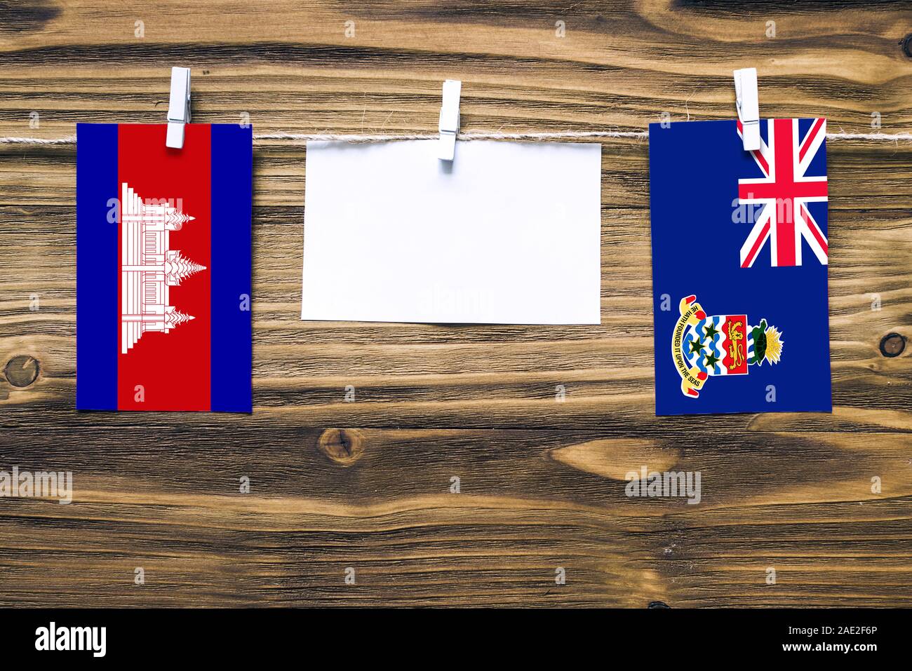 Appendere bandiere della Cambogia e delle Isole Cayman attaccata alla corda con vestiti perni con copia spazio bianco sulla nota carta su sfondo di legno.re diplomatica Foto Stock