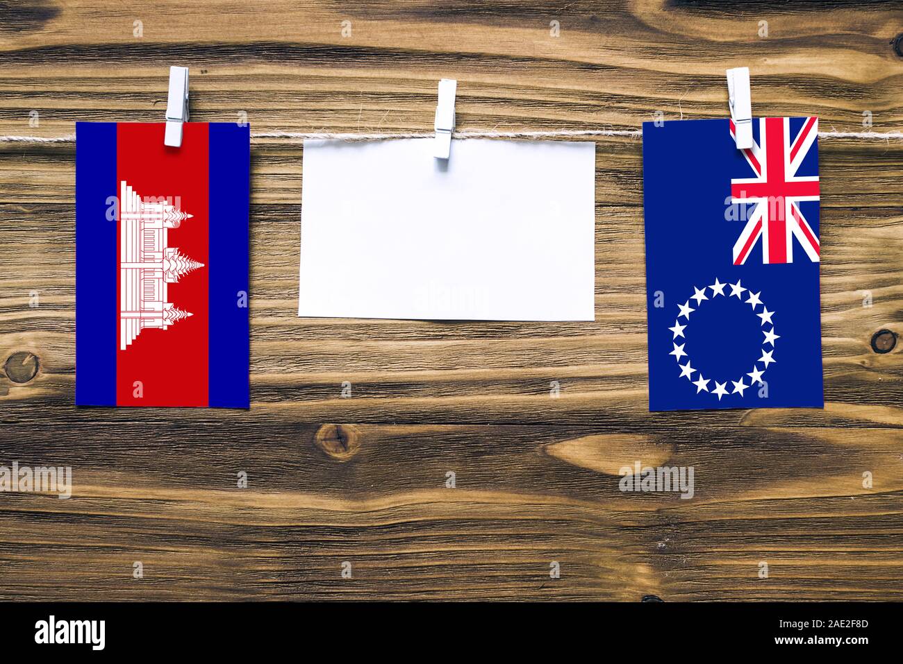 Appendere bandiere della Cambogia e le Isole Cook attaccata alla corda con vestiti perni con copia spazio bianco sulla nota carta su sfondo di legno.Diplomatic rela Foto Stock