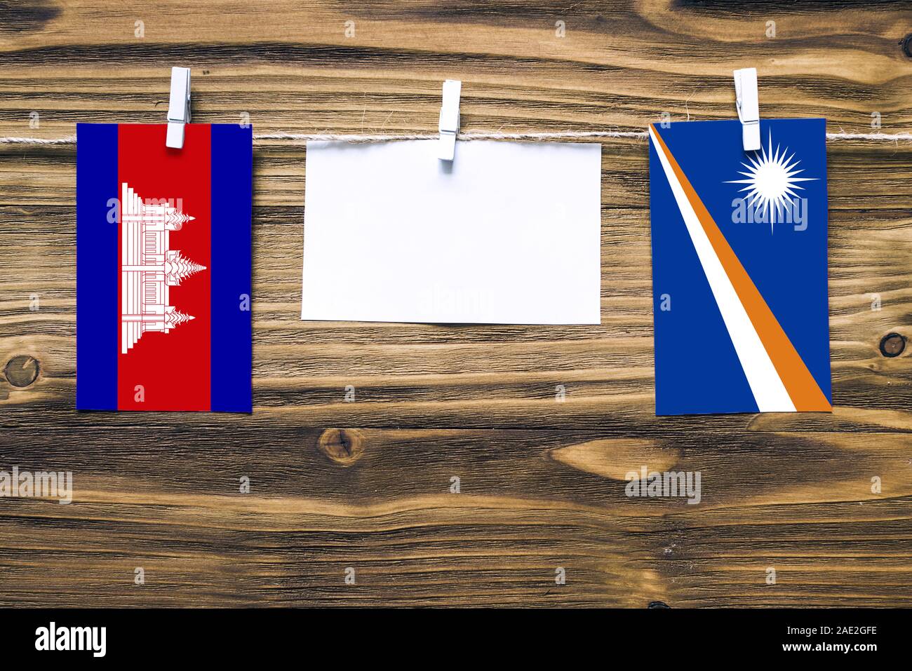 Appendere bandiere della Cambogia e Isole Marshall attaccata alla corda con vestiti perni con copia spazio bianco sulla nota carta su sfondo di legno.Diplomatic Foto Stock