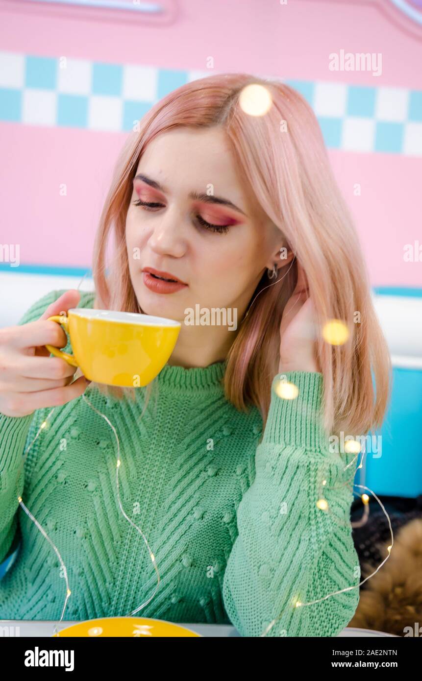 Pretty girl bere il tè in cafe. Rosa e sfondo blu Foto Stock