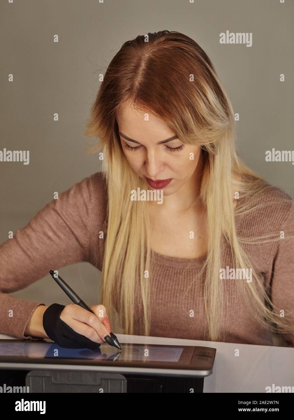 Ragazza artista disegna una penna digitale su un tablet PC professionale nel suo studio Foto Stock