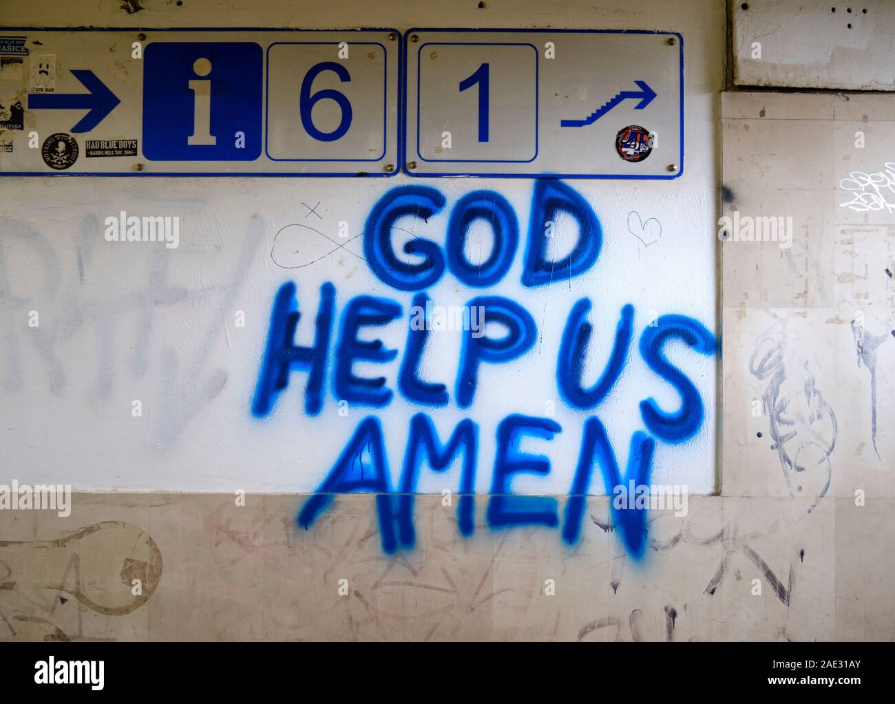 "Dio ci aiutano, Amen" graffiti in vernice blu su una stazione ferroviaria a parete, con i numeri della piattaforma Foto Stock