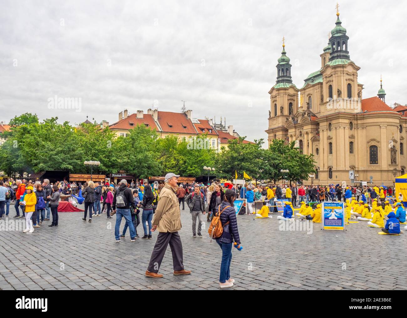 I turisti a piedi da un gruppo di Falun Dafa membri meditando e di esercitare nella città vecchia piazza con la Chiesa di San Nicola in background Praga Repubblica Ceca. Foto Stock