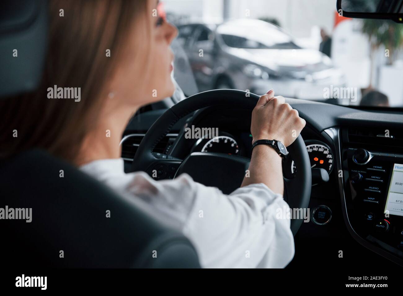 Non può aspettare fino a quando ottengo sulla strada. Bella ragazza bionda seduta nella nuova vettura con i moderni interni neri Foto Stock
