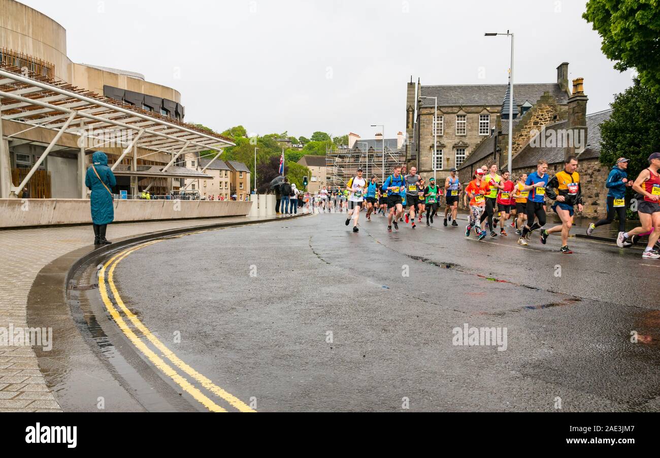 Maratona di Edimburgo Festival 2019 podisti corrono passando da Holyrood Palace & edificio del Parlamento scozzese sul giorno di pioggia, Edimburgo, Scozia, Regno Unito Foto Stock