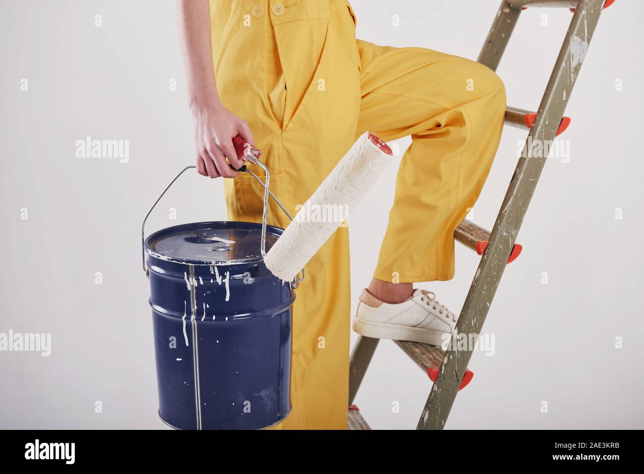 Gambe è sul gradino. Bella bruna in uniforme di colore giallo e blu con la benna si erge accanto alla scaletta Foto Stock