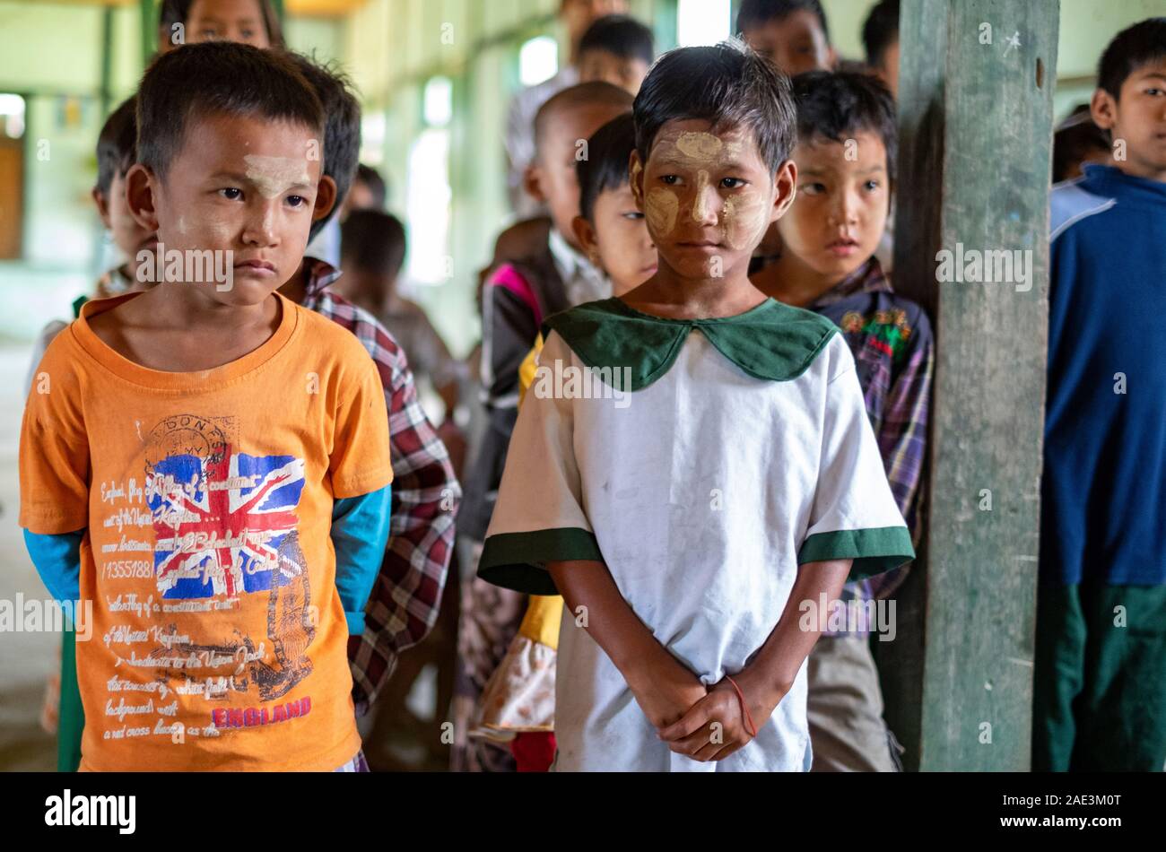 Ragazzo giovane studenti con facce in polvere la linea fino a cantare canzoni a un assembly in un villaggio rurale scuola lungo il fiume Chindwin in Myanmar (Birmania) Foto Stock