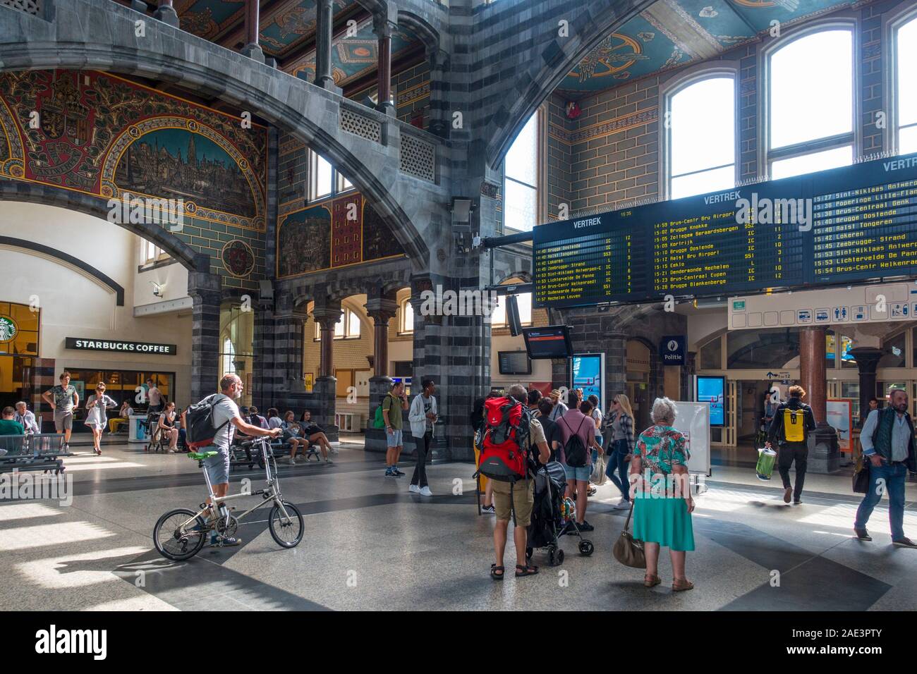 I viaggiatori / pendolari guardando gli orari in sala partenze dell'Gent-Sint-Pieters / San Pietro stazione ferroviaria a Gand, Fiandre Orientali, Belgio Foto Stock