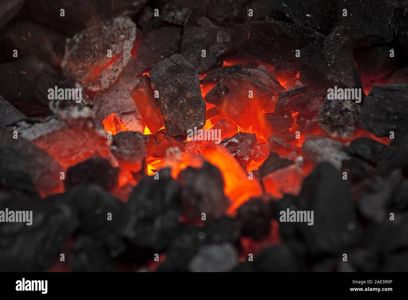 Embers glow in un falò, chiudere la vista. Incendio, calore, carbone e cenere con scintille volanti. Foto Stock