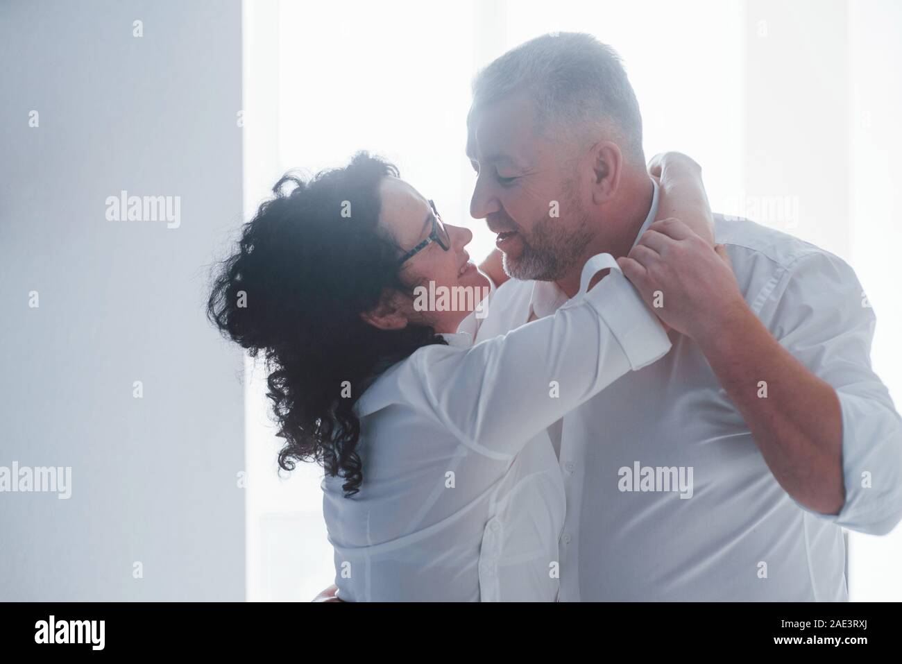 Senior l'uomo e sua moglie in maglia bianca hanno una cena romantica sulla cucina Foto Stock