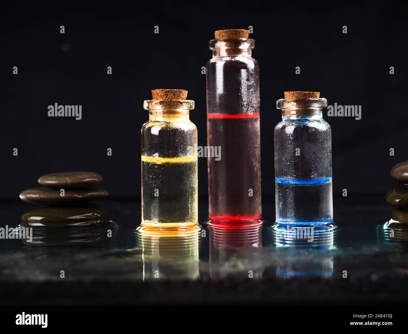 Tre fiale colorate in vetro liquido con fondo nero per la ricerca medica. In un laboratorio chimico fiala di vetro con tappo in sughero in nero. Diversi Foto Stock