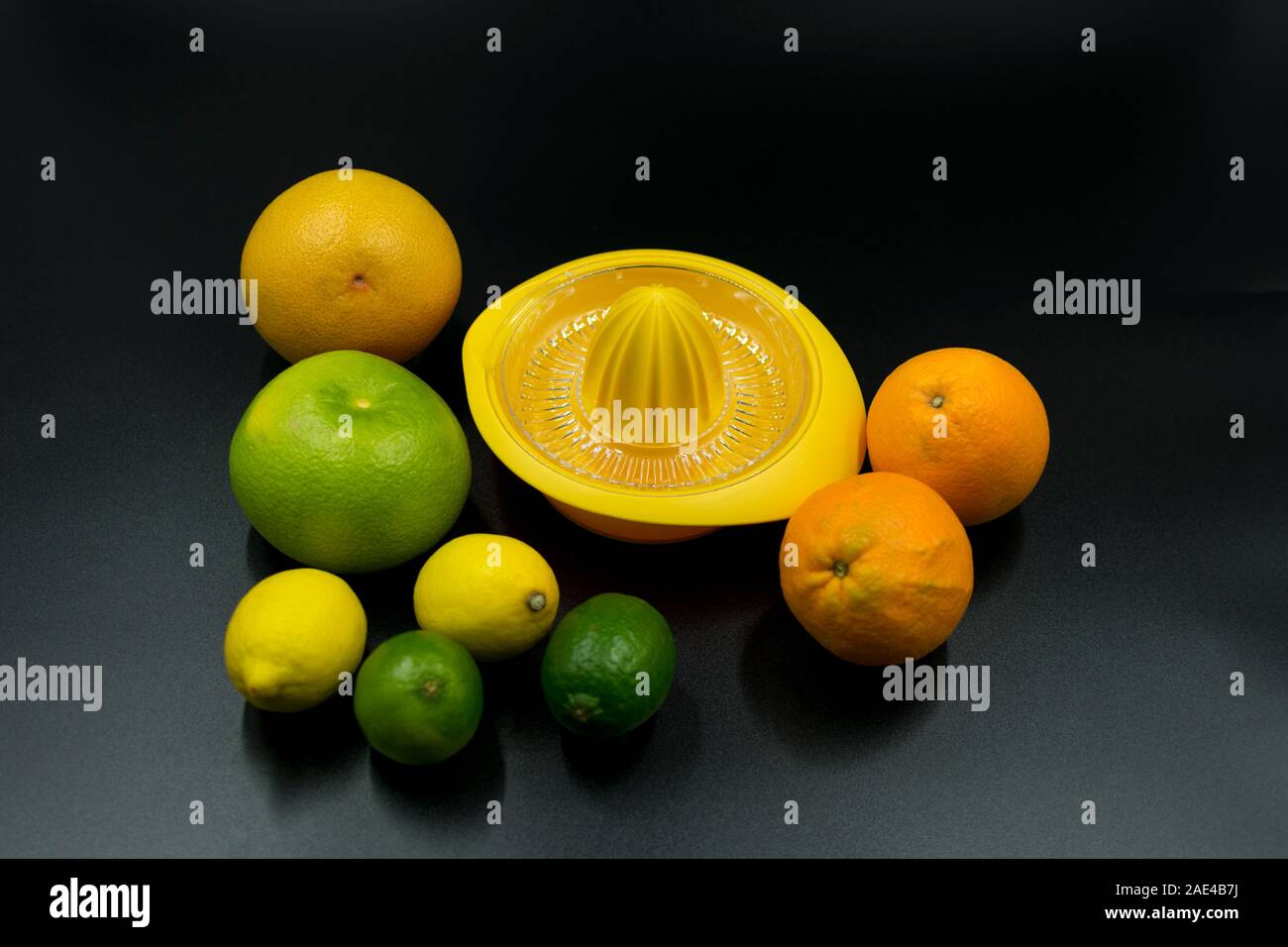 Giallo spremiagrumi con arance, pompelmi, cedri e limoni su sfondo nero. Foto Stock