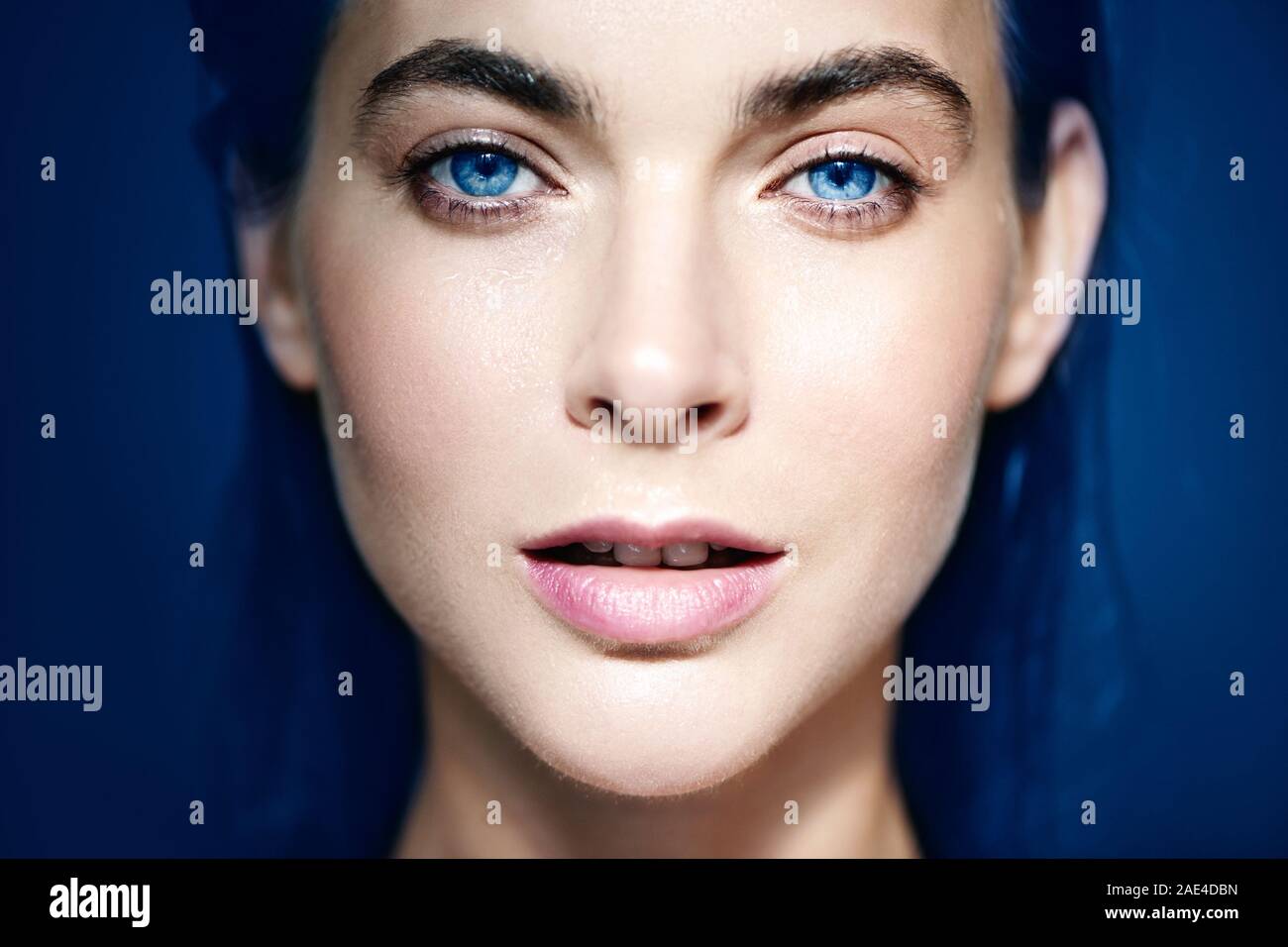 Chiuso su Ritratto di Belle blue-eyed donna su sfondo blu. Foto Stock