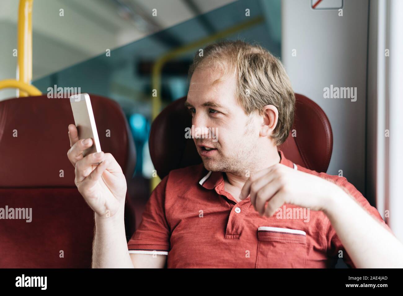 Uomo sorridente in un treno suburbano facendo una selfie sparare dal telefono cellulare Foto Stock