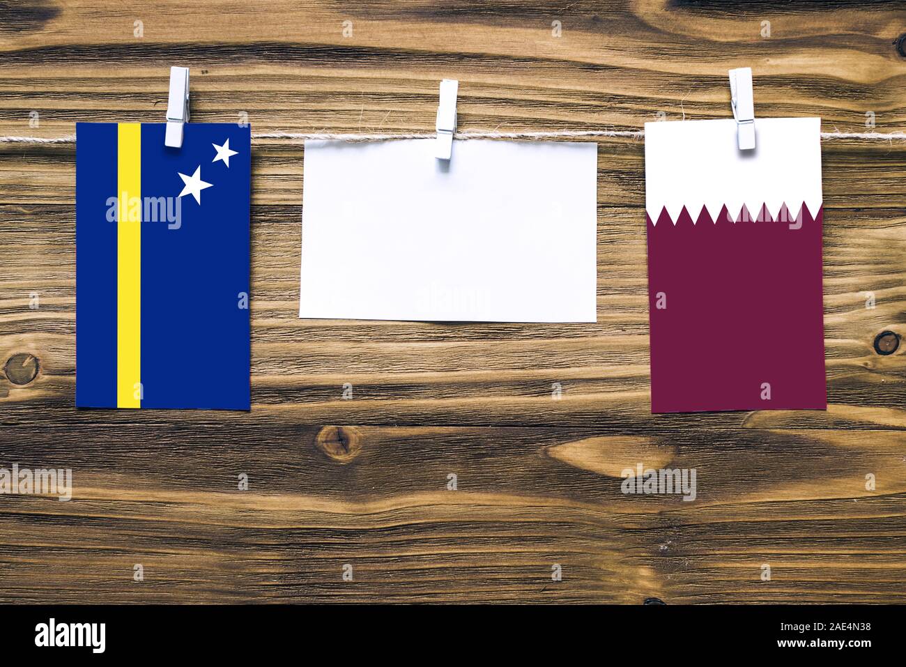 Appendere bandiere di Curacao e Qatar attaccata alla corda con vestiti perni con copia spazio bianco sulla nota carta su sfondo di legno.Le relazioni diplomatiche essere Foto Stock