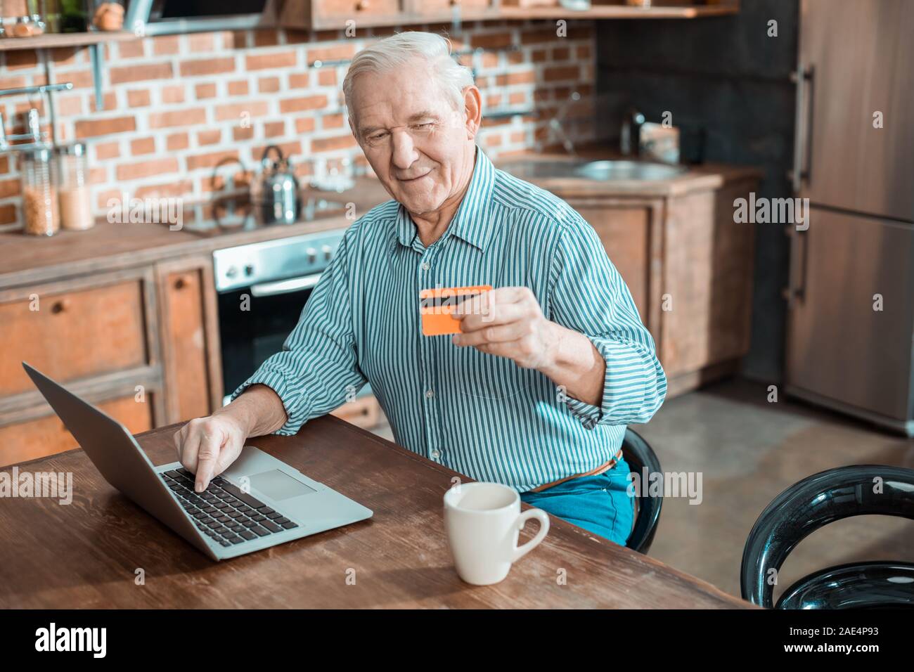 Gioioso uomo anziano rendendo il pagamento on-line Foto Stock