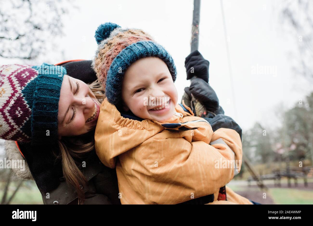 Ritratto di madre e figlio a suonare in un parco sotto la pioggia in inverno Foto Stock