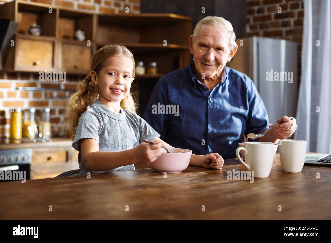 Felice bambina avente la colazione con il suo nonno Foto Stock