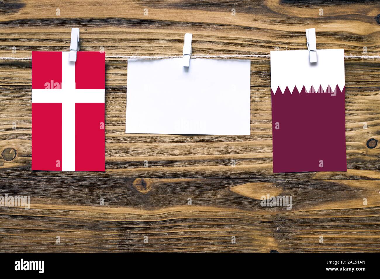 Appendere bandiere di Danimarca e Qatar attaccata alla corda con vestiti perni con copia spazio bianco sulla nota carta su sfondo di legno.Le relazioni diplomatiche essere Foto Stock