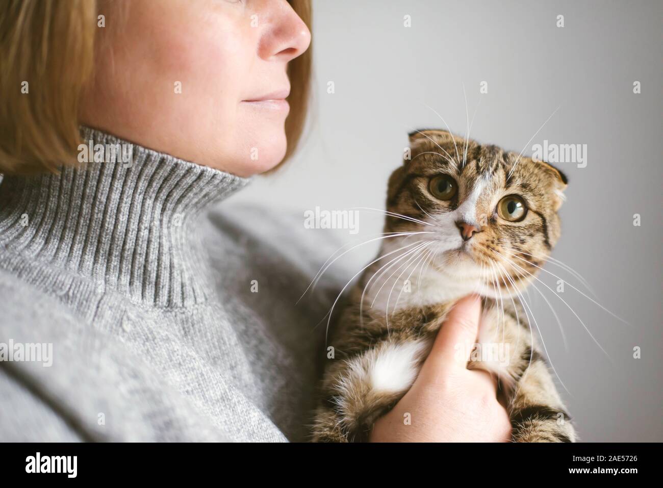 Donna che mantiene bel gatto su sfondo bianco Foto Stock