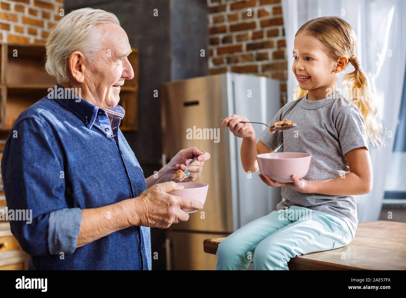 Allegro bambina avente la colazione con il suo nonno Foto Stock