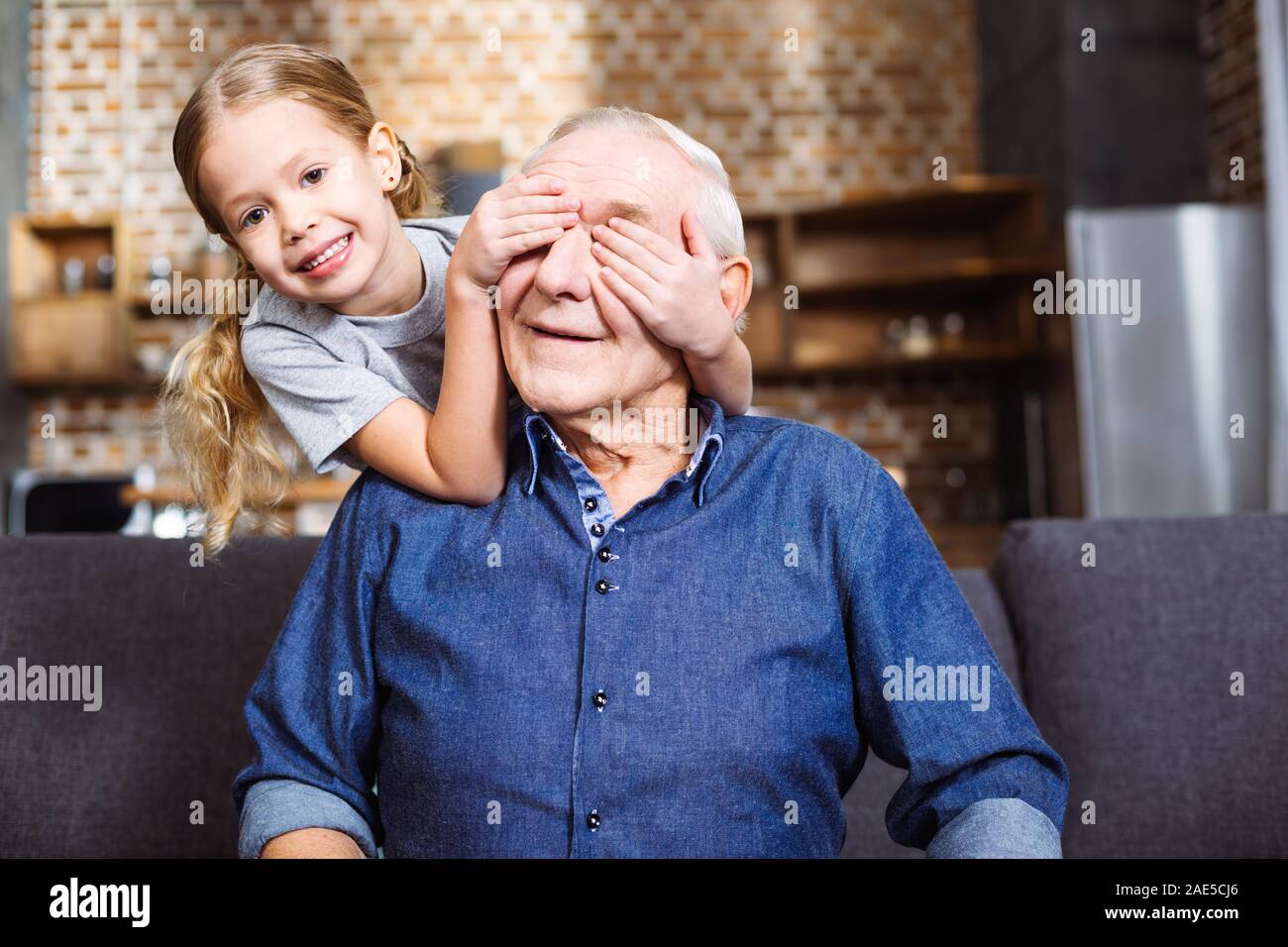 Overjoyed bambina chiudendo gli occhi di suo nonno Foto Stock