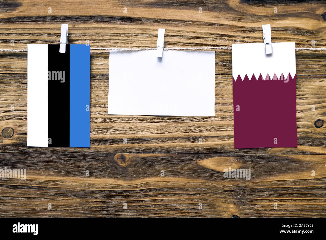 Appendere bandiere di Estonia e Qatar attaccata alla corda con vestiti perni con copia spazio bianco sulla nota carta su sfondo di legno.Le relazioni diplomatiche essere Foto Stock