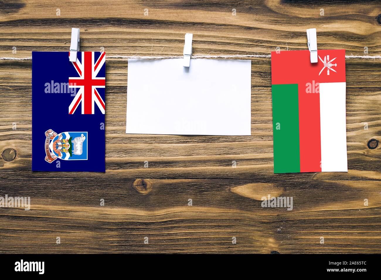 Appendere bandiere delle Isole Falkland e Oman attaccata alla corda con vestiti perni con copia spazio bianco sulla nota carta su sfondo di legno.Diplomatic rela Foto Stock