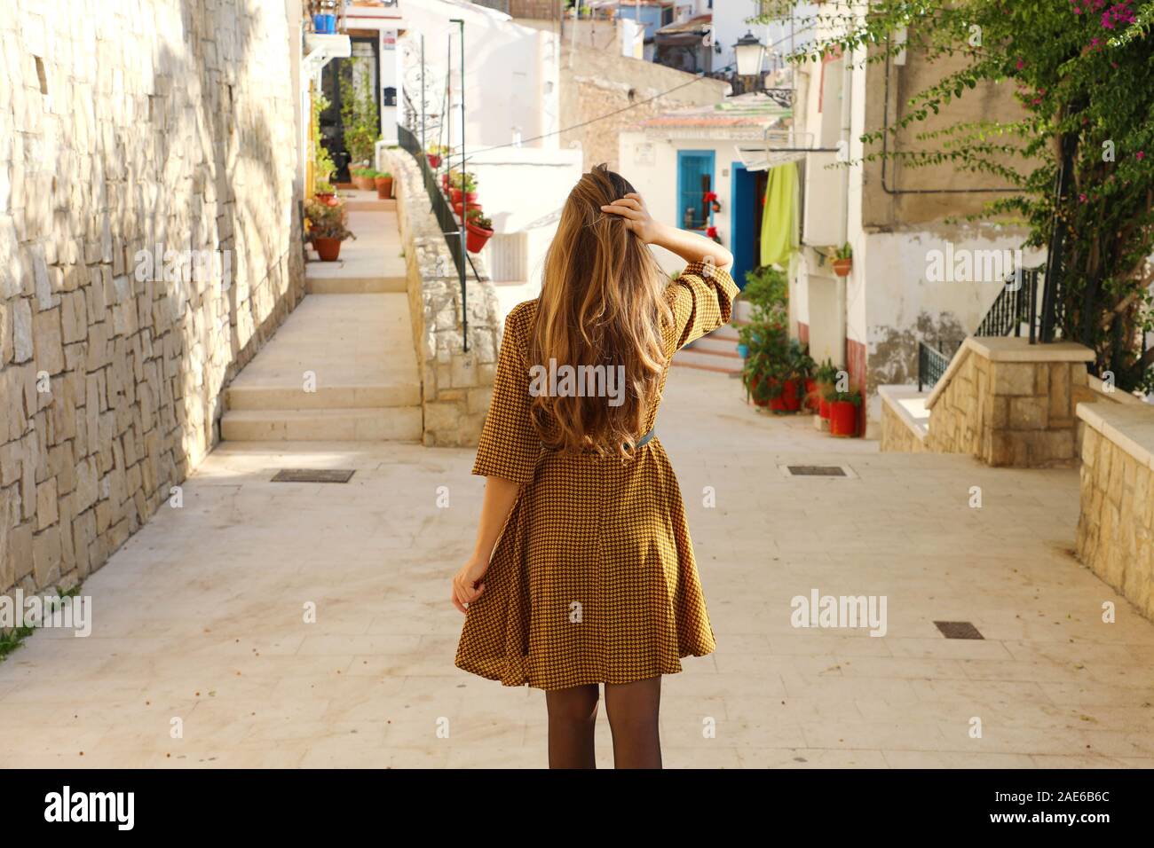 Curioso giovane donna a piedi nella vecchia strada di Alicante, Spagna. Vista posteriore di felice allegro ragazza visitando il sud dell'Europa. Foto Stock