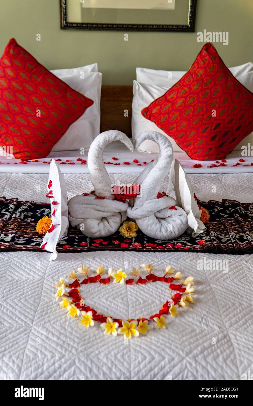 Romantico letto con fiori e asciugamani a forma di cigni con cuori e  cuscini rossi Foto stock - Alamy