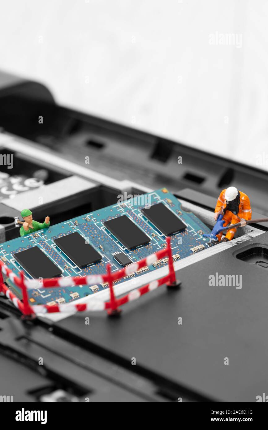 Miniatura modello in scala dei lavoratori dell'edilizia l'installazione di RAM nello slot di memoria su un computer portatile Foto Stock