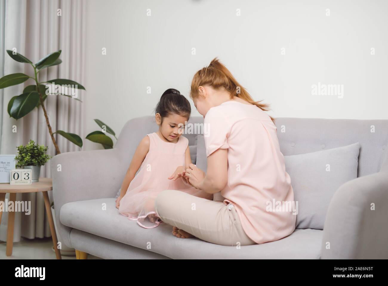 Mom utilizza rosa smalto per unghie per dipingere la sua figlia carino nail per rendere la sua più felice e più bello Foto Stock