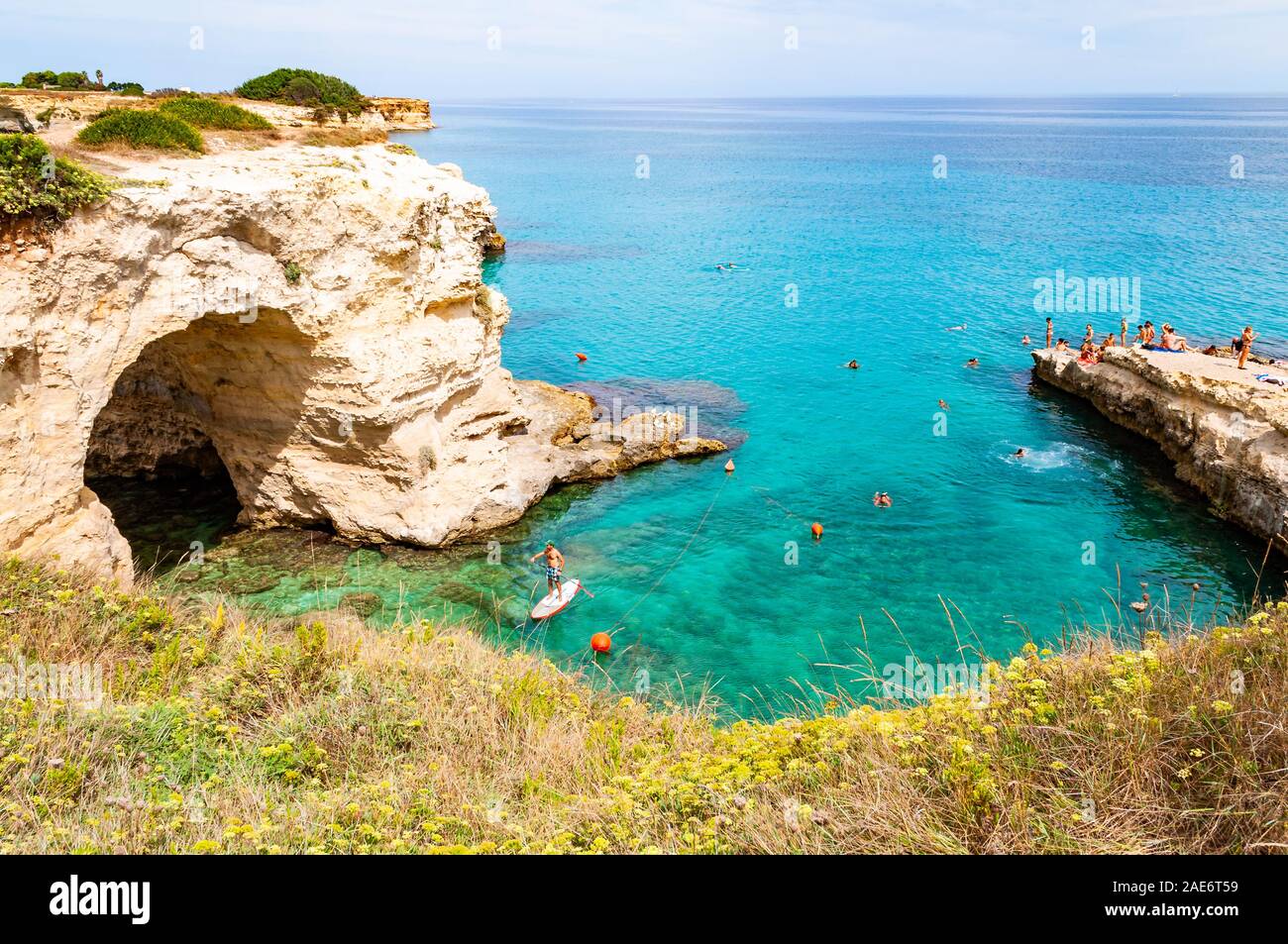 Tropea in Calabria, Italia - 09 Settembre 2019: persone diving dalla scogliera piatta, prendere il sole, nuotare nel mare cristallino dell'acqua sulla spiaggia rocciosa di Foto Stock