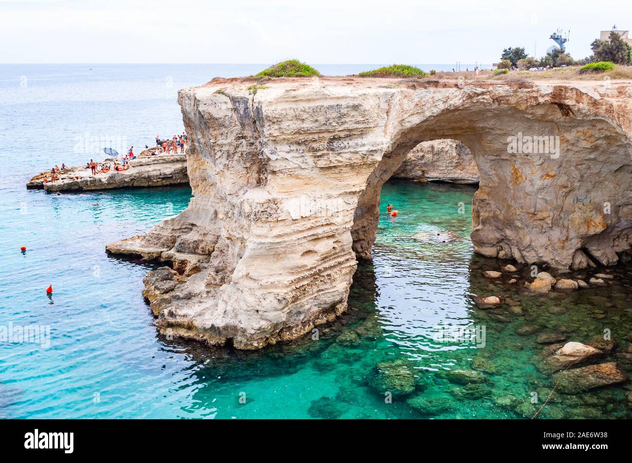 Torre Sant Andrea, Puglia, Italia - 09 Settembre 2019: persone diving dalla scogliera, prendere il sole, nuotare nel mare cristallino dell'acqua sulla spiaggia rocciosa Foto Stock