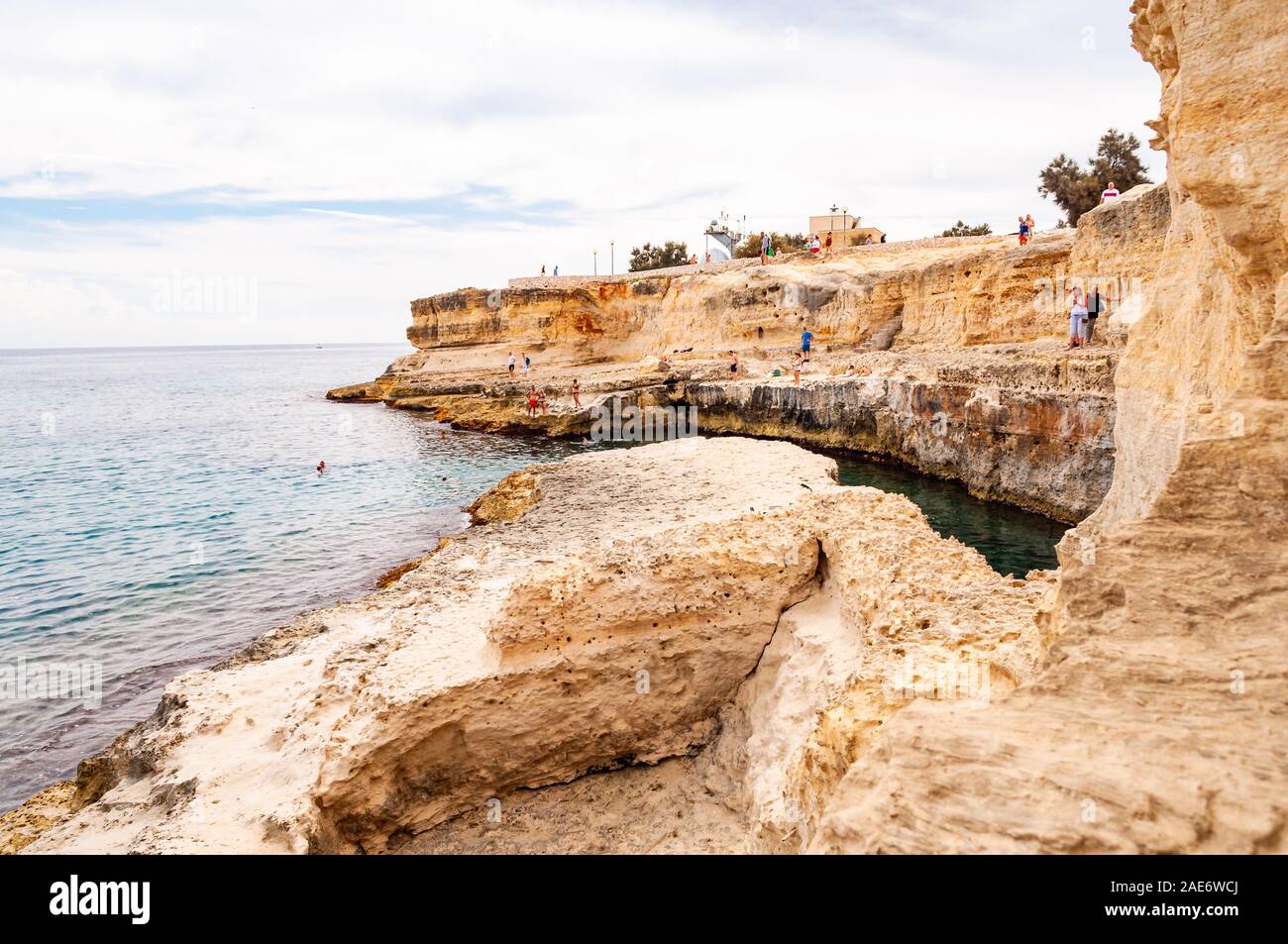 Torre Sant Andrea, Puglia, Italia - 09 Settembre 2019: persone diving dalla scogliera, prendere il sole, nuotare nel mare cristallino dell'acqua sulla spiaggia rocciosa Foto Stock