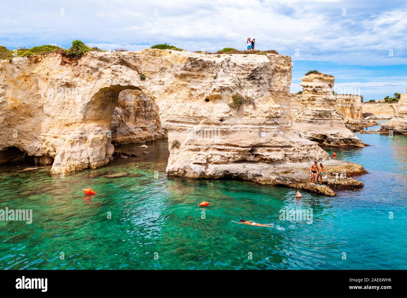 Torre Sant Andrea, Puglia, Italia - 09 Settembre 2019: persone diving dalla scogliera, prendere il sole, nuotare nel mare cristallino dell'acqua sulla spiaggia rocciosa Foto Stock