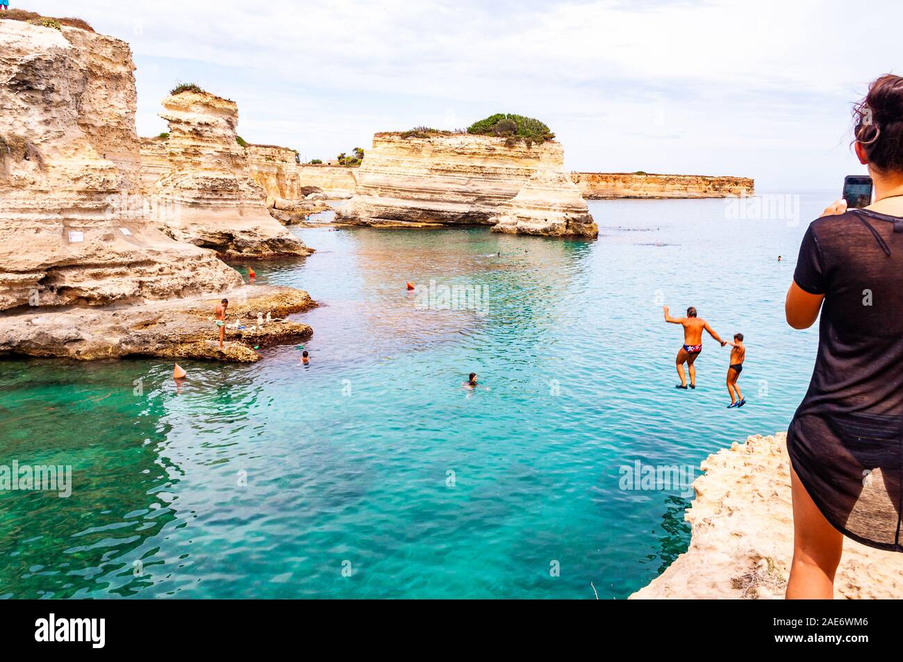 Torre Sant Andrea, Puglia, Italia - 09 Settembre 2019: persone diving dalla scogliera, prendere il sole, nuotare nel mare cristallino dell'acqua sulla spiaggia rocciosa Foto Stock